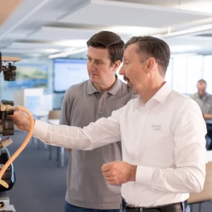 Truma Academy Mitarbeiter erklärt einem Kunden mobile Heiztechnik an großem Model