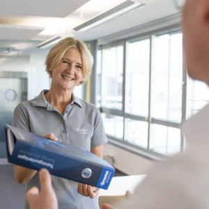 Lächelnde Mitarbeiterin der Truma Academy mit Ordner